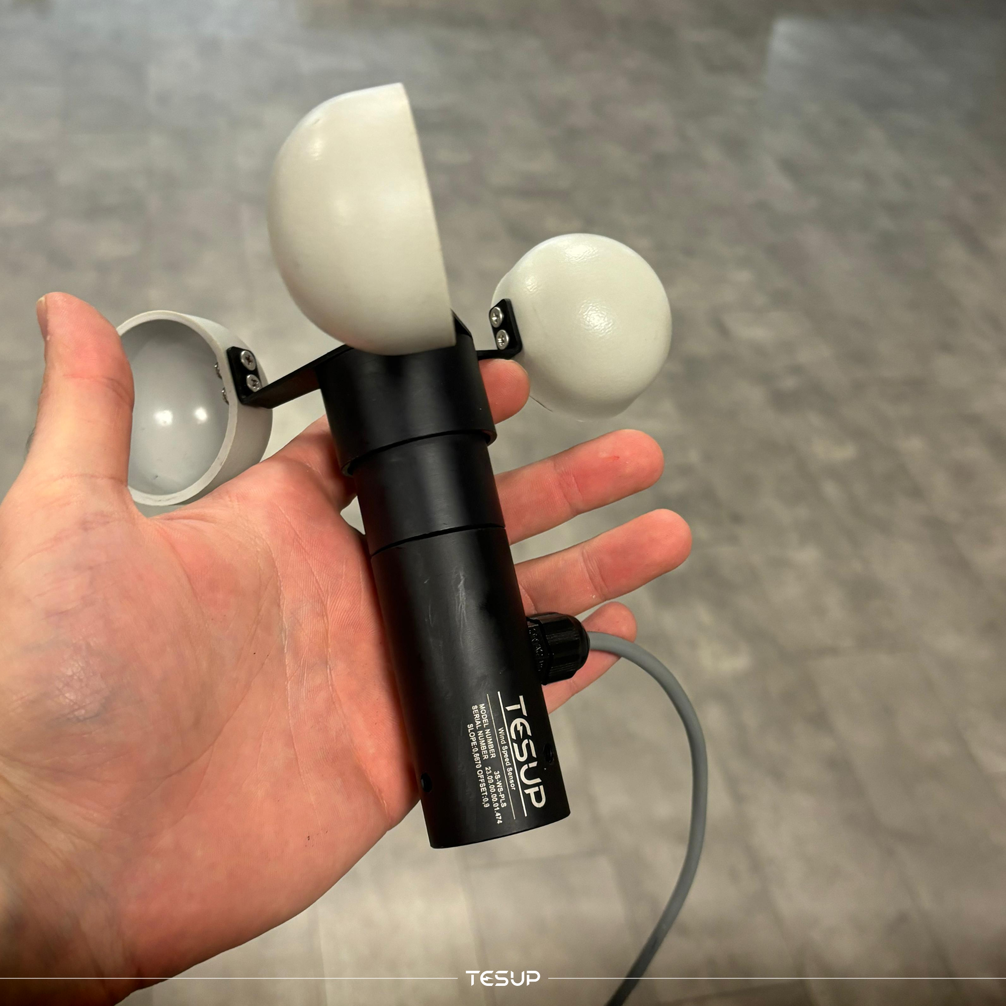 Een cupanemometer in één hand, de sensor waarmee de windsnelheid op de locatie wordt gemeten voordat een turbine wordt gekozen