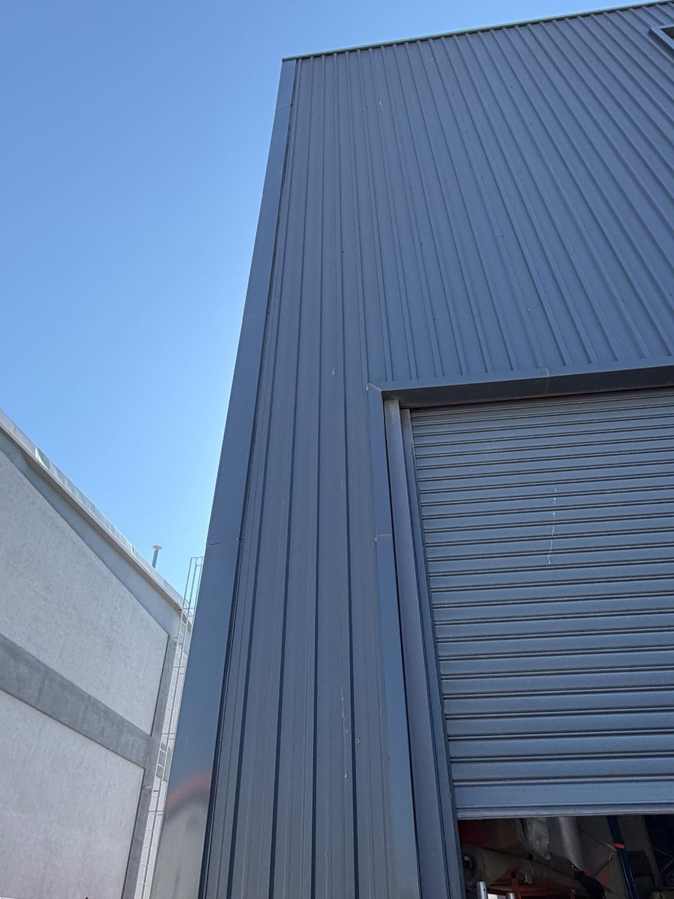 The exterior of the Wekraft production building, dark grey profiled steel cladding and a roller shutter door