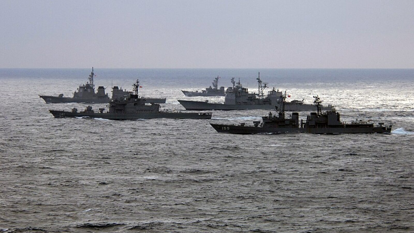 Oorlogsschepen van twee marines varen dicht bij elkaar door een grijze zee