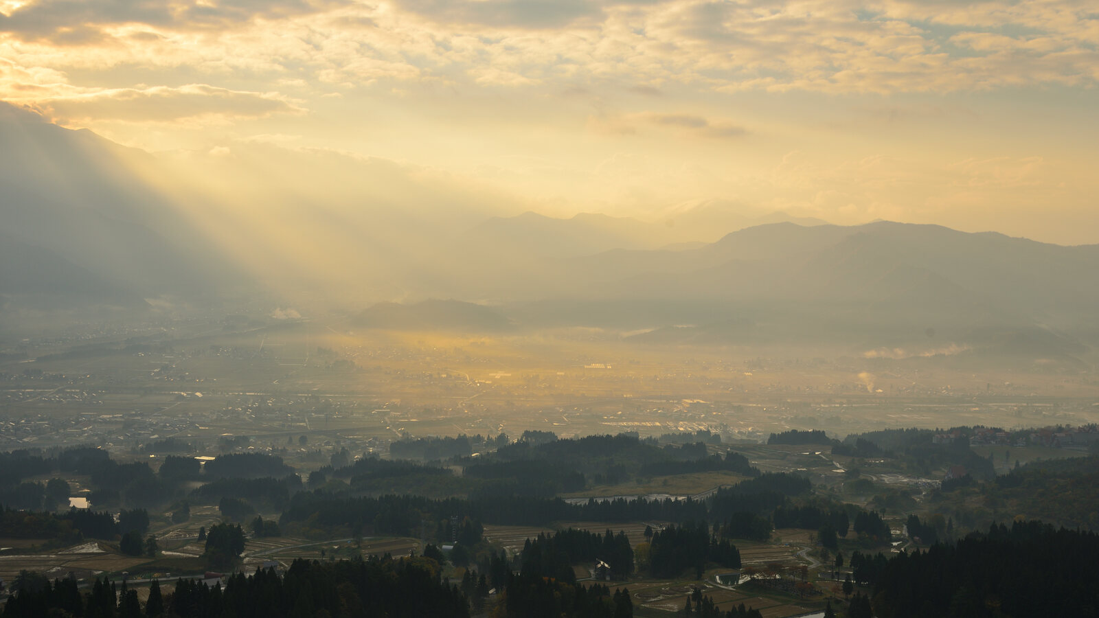 Vroege ochtendnevel boven de rijstvelden van Minamiuonuma, prefectuur Niigata, met zonlicht dat door de wolken breekt